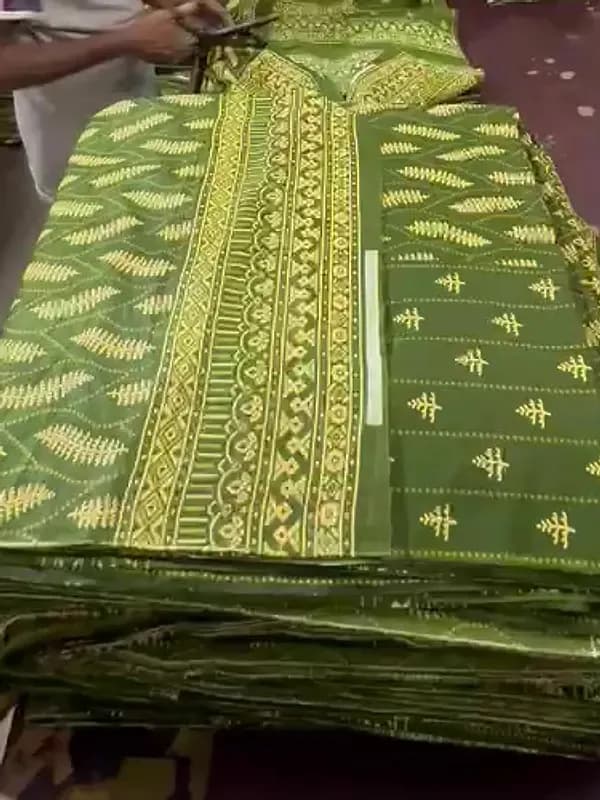 Printed green suits, folded and stacked by hand